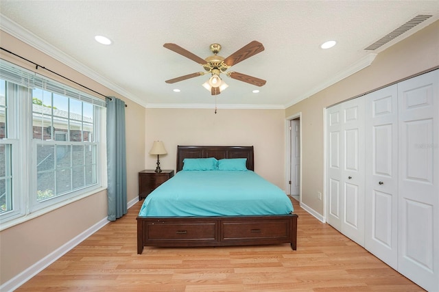 bedroom featuring ceiling fan, a closet, ornamental molding, and light hardwood / wood-style flooring