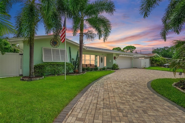 single story home with a garage and a lawn