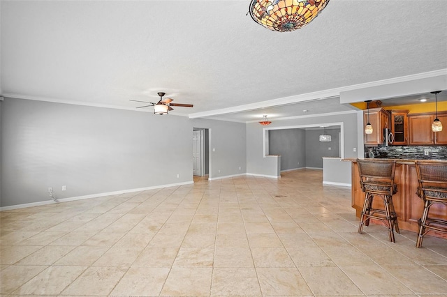 tiled living room with a textured ceiling, ceiling fan, and crown molding