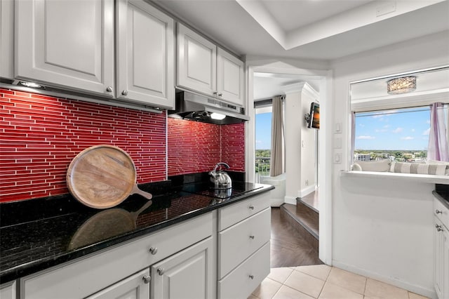 kitchen featuring light tile patterned flooring, dark stone countertops, decorative backsplash, and white cabinets