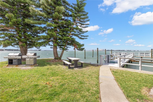 view of dock with a lawn and a water view