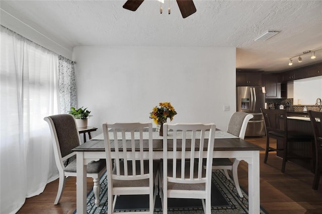 dining room with dark wood-type flooring, ceiling fan, a textured ceiling, and rail lighting