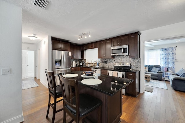 kitchen featuring a kitchen island, stainless steel appliances, wood-type flooring, sink, and a textured ceiling