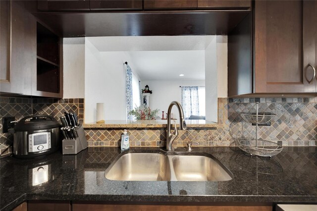 kitchen featuring backsplash, sink, and dark stone counters