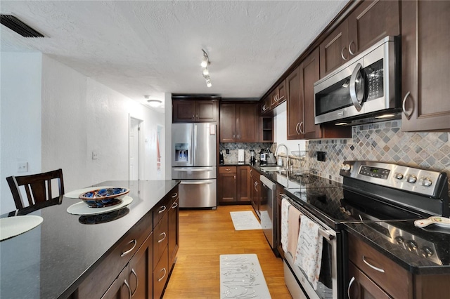 kitchen featuring tasteful backsplash, sink, dark brown cabinets, stainless steel appliances, and light hardwood / wood-style flooring