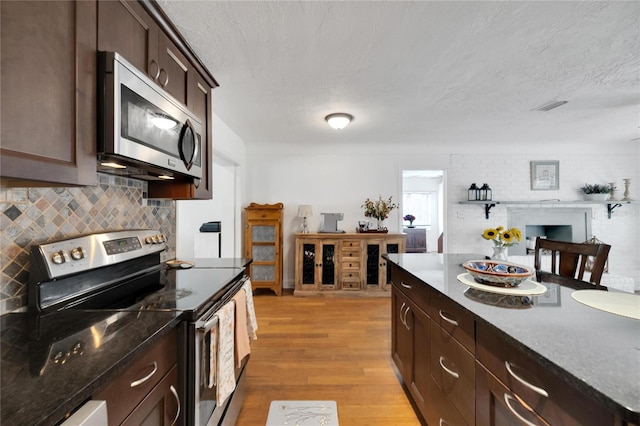 kitchen featuring tasteful backsplash, a textured ceiling, light hardwood / wood-style flooring, dark brown cabinetry, and stainless steel appliances