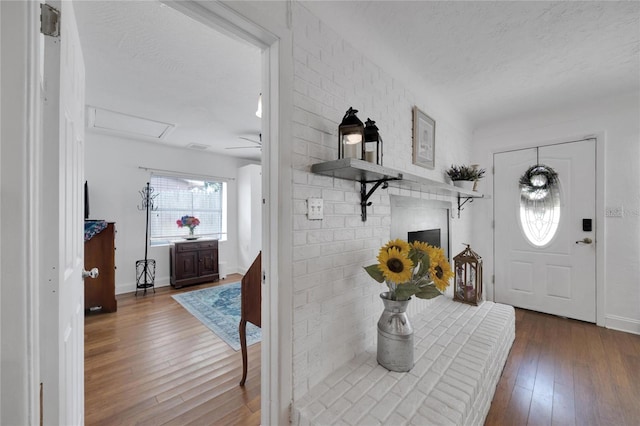 foyer with brick wall, a textured ceiling, and hardwood / wood-style flooring