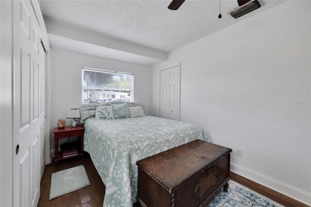 bedroom with dark wood-type flooring, a textured ceiling, and ceiling fan