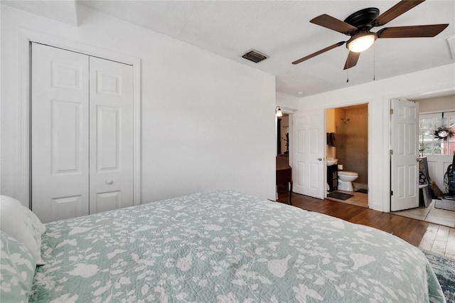 bedroom with ceiling fan, hardwood / wood-style flooring, a closet, and ensuite bath