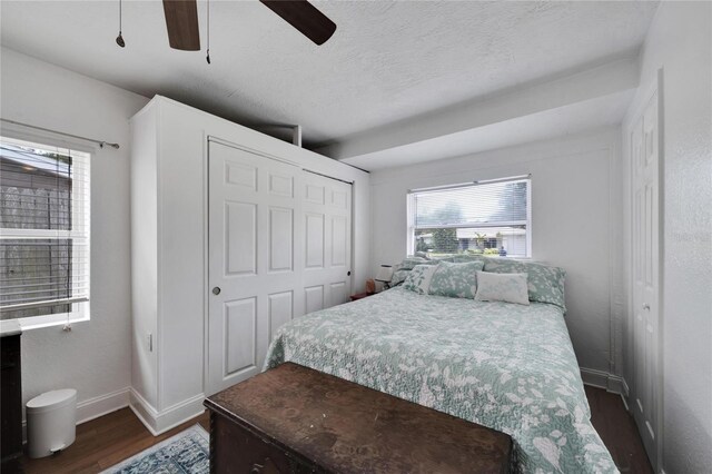 bedroom with dark wood-type flooring, a textured ceiling, a closet, and ceiling fan