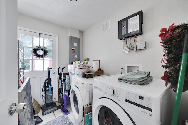 laundry room featuring a textured ceiling, electric panel, washer and clothes dryer, and light tile patterned floors