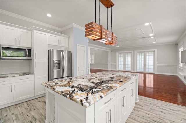 kitchen with light stone countertops, white cabinetry, pendant lighting, appliances with stainless steel finishes, and ornamental molding