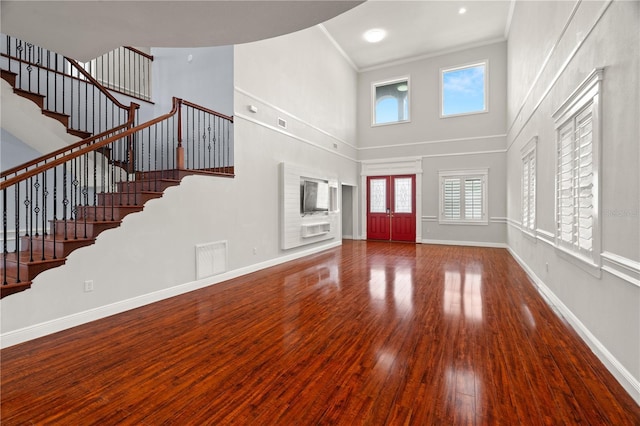 foyer with french doors, a towering ceiling, wood-type flooring, and ornamental molding