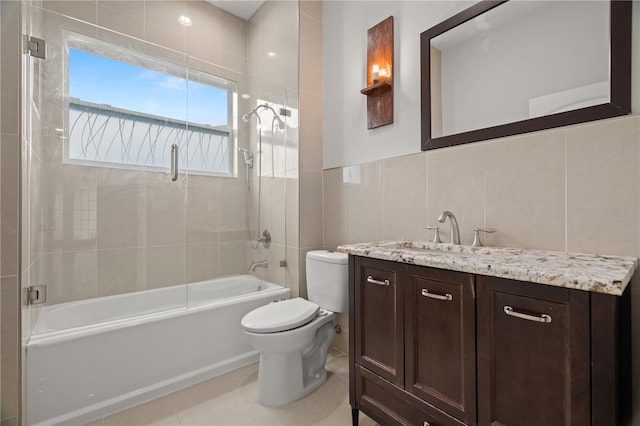 full bathroom featuring tile patterned floors, vanity, tiled shower / bath combo, tile walls, and toilet