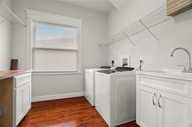 laundry area with cabinets, dark hardwood / wood-style flooring, washing machine and dryer, and sink