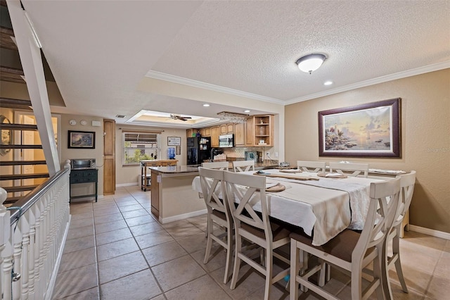 dining space with ornamental molding, ceiling fan, a raised ceiling, a textured ceiling, and light tile patterned floors