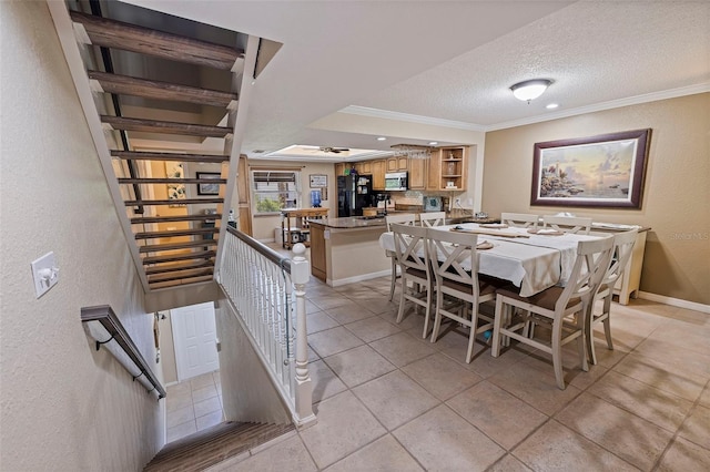 tiled dining space with a textured ceiling and crown molding