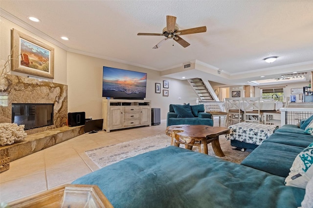 tiled living room featuring a textured ceiling, ornamental molding, ceiling fan, and a premium fireplace