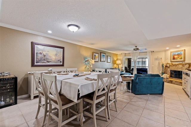 tiled dining area featuring ceiling fan, crown molding, a textured ceiling, and wine cooler