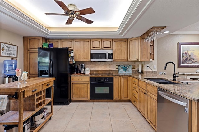 kitchen with dark stone countertops, sink, light tile patterned flooring, a tray ceiling, and black appliances