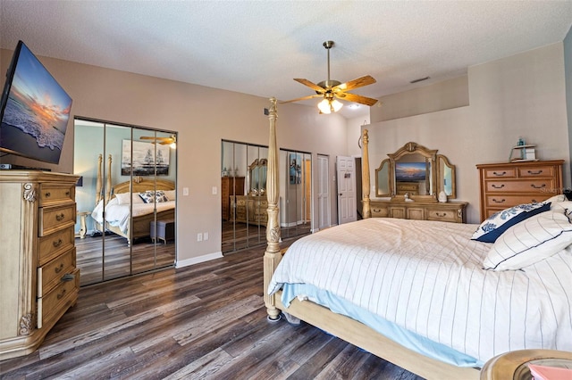 bedroom with two closets, a textured ceiling, lofted ceiling, ceiling fan, and dark hardwood / wood-style floors