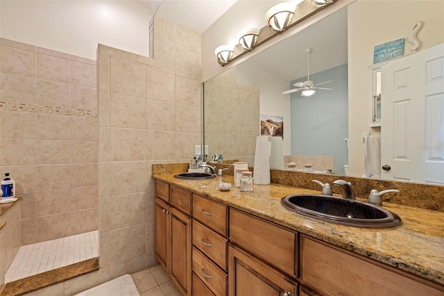 bathroom featuring tile patterned floors, a tile shower, tile walls, ceiling fan, and vanity