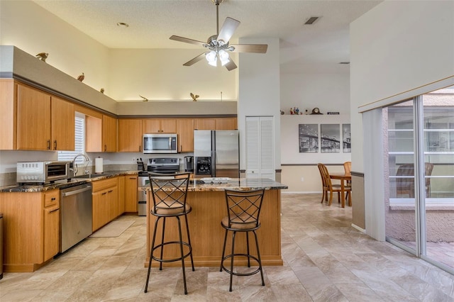 kitchen with a high ceiling, a center island, stainless steel appliances, and sink