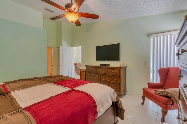 tiled bedroom with ceiling fan and a textured ceiling