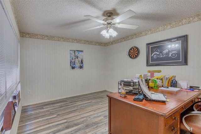 home office featuring hardwood / wood-style floors, ceiling fan, and a textured ceiling