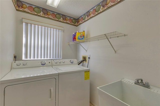 laundry room featuring a textured ceiling, washing machine and dryer, and sink