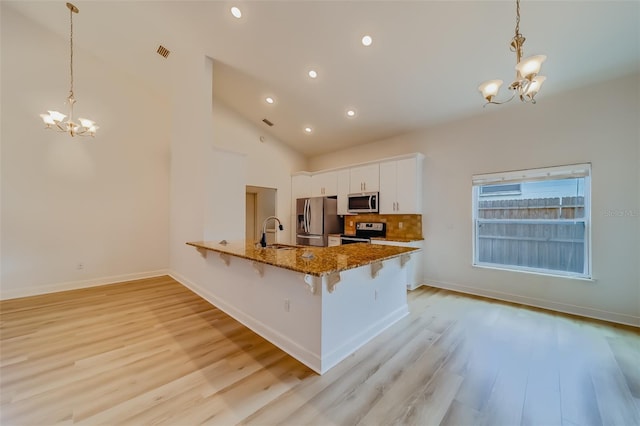 kitchen with stainless steel appliances, sink, kitchen peninsula, light hardwood / wood-style floors, and white cabinetry