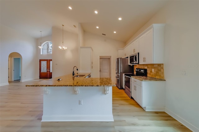 kitchen with white cabinets, light hardwood / wood-style floors, appliances with stainless steel finishes, and high vaulted ceiling