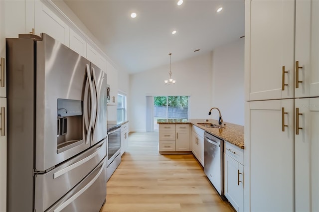 kitchen with lofted ceiling, kitchen peninsula, light hardwood / wood-style floors, appliances with stainless steel finishes, and sink