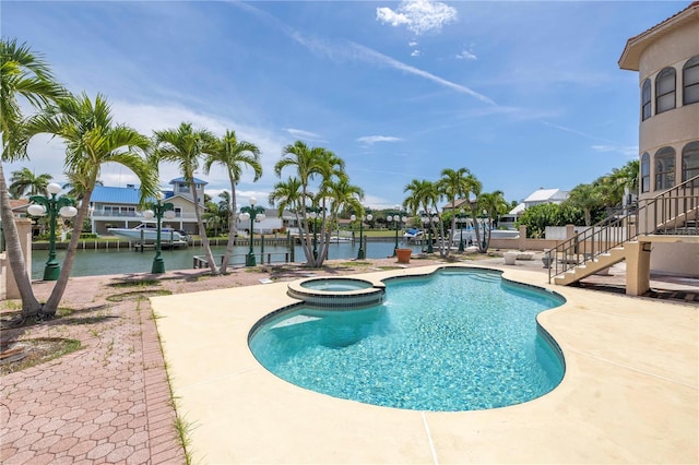 view of pool with an in ground hot tub, a water view, and a patio area