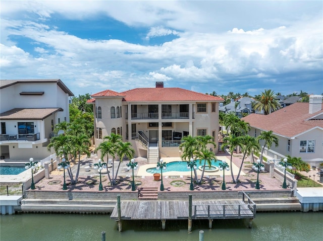 back of property with a water view and a patio area