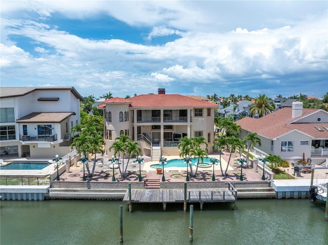 back of house featuring a water view, a balcony, and a patio area