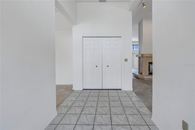 hall featuring a towering ceiling and light tile patterned floors