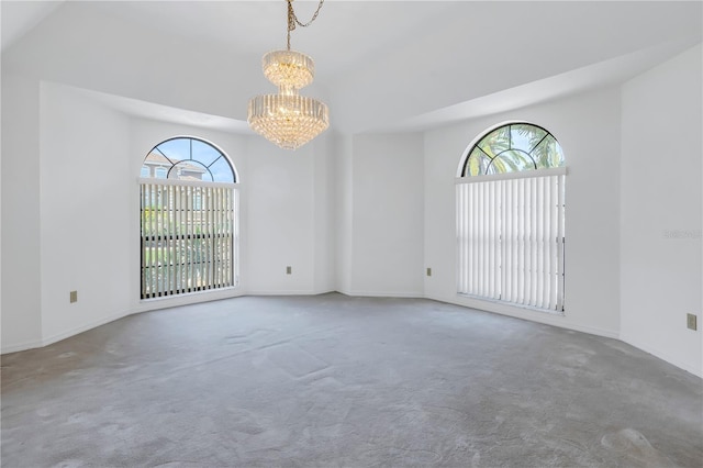 carpeted spare room with plenty of natural light and a notable chandelier