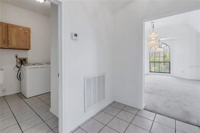 laundry area with cabinets, washer / clothes dryer, a notable chandelier, and light tile patterned floors