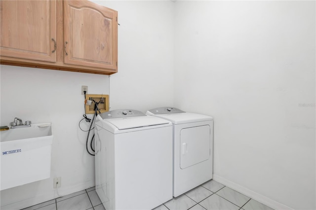 washroom featuring independent washer and dryer, sink, cabinets, and light tile patterned floors