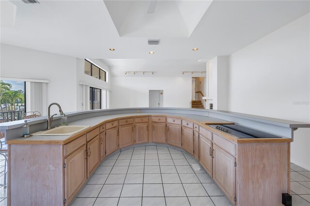 kitchen with light brown cabinetry, sink, light tile patterned floors, and a kitchen bar