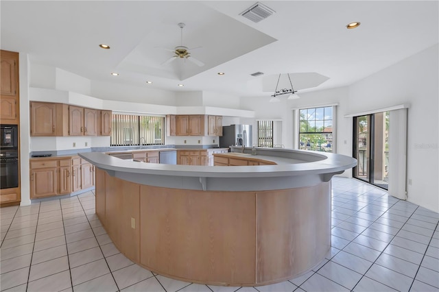 kitchen featuring a spacious island, light tile patterned floors, and black appliances