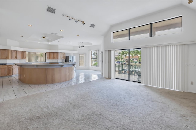 kitchen with stainless steel refrigerator with ice dispenser, a center island, high vaulted ceiling, light carpet, and ceiling fan