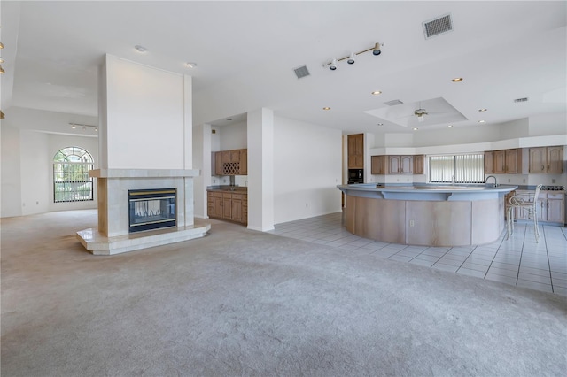 kitchen with light colored carpet, a tile fireplace, ceiling fan, and a kitchen island