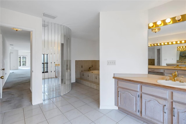 bathroom with tile patterned flooring, vanity, and tiled bath