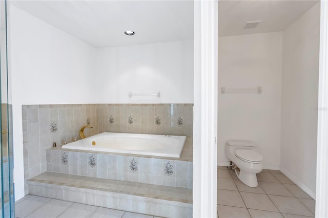 bathroom featuring tile patterned flooring, a relaxing tiled tub, and toilet