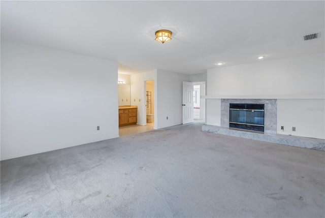 unfurnished living room featuring light colored carpet and a fireplace