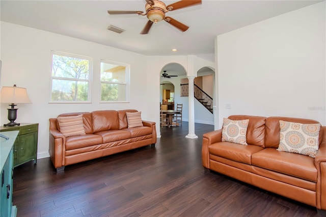 living room featuring decorative columns, dark hardwood / wood-style floors, and ceiling fan