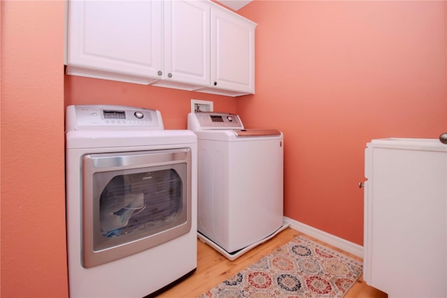 laundry area with separate washer and dryer, cabinets, and light wood-type flooring