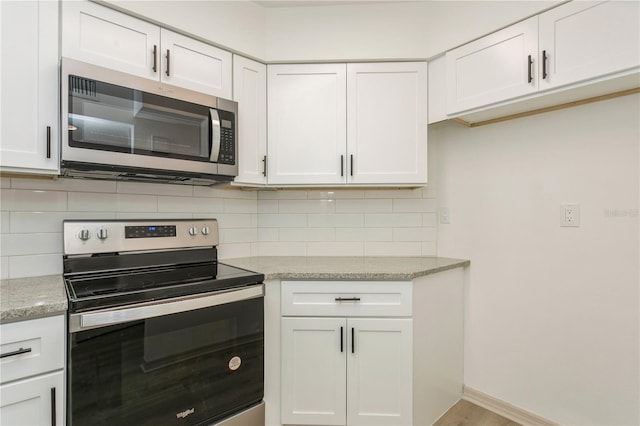 kitchen featuring white cabinets, appliances with stainless steel finishes, and light stone counters